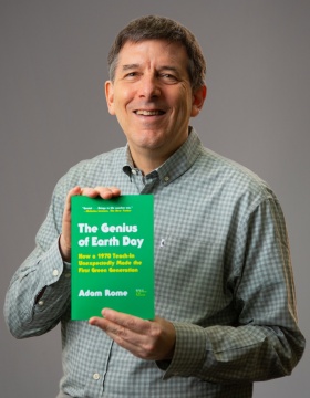 Zoom image: Head shot of U B environmental historian Adam Rome holding his book, "The Genius of Earth Day." 