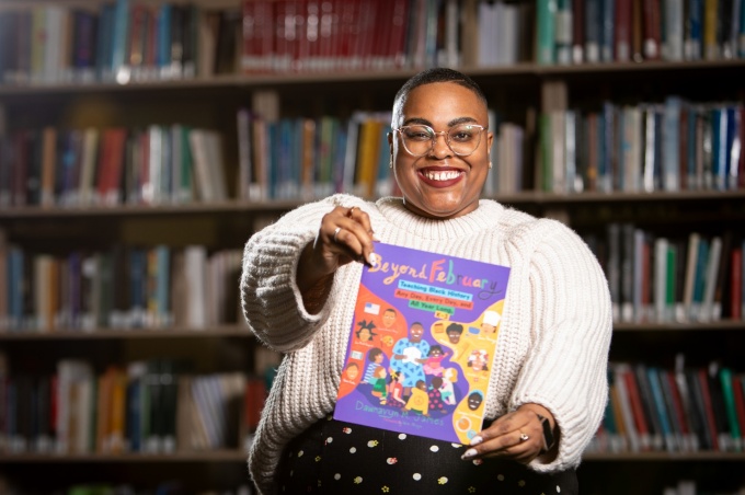 Dawnavyn James holds a picture book inside a library. 