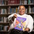 Dawnavyn James holds a picture book inside a library. 