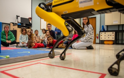 School age children watch a demonstration of UB's robot dog. 