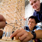 People working with a tower of wooden parts. 