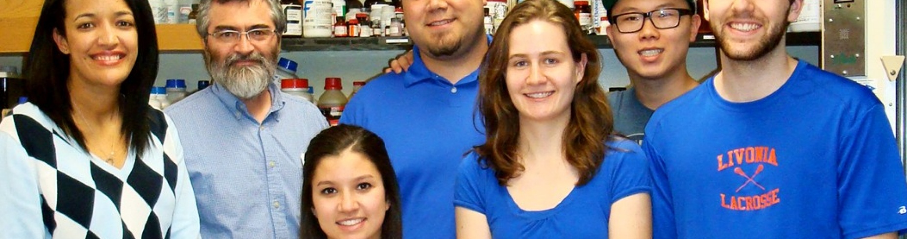 Students grouped in a laboratory, smiling, with their professor.