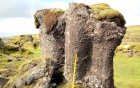 A large rocky formation in the middle of a field. 