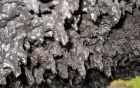 A shaggy, glassy rock surface that is solid but looks like it is dripping. 