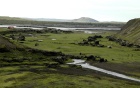 Green fields with dotted with dark, rocky pillars. 