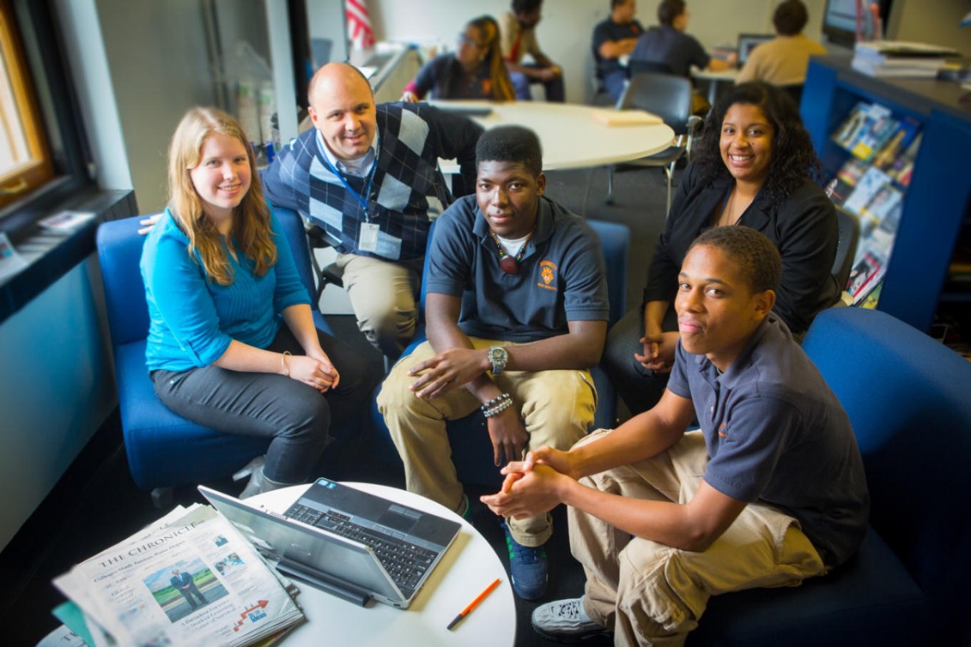 Nathan Daun-Barnett with students seated around an open laptop computer. 