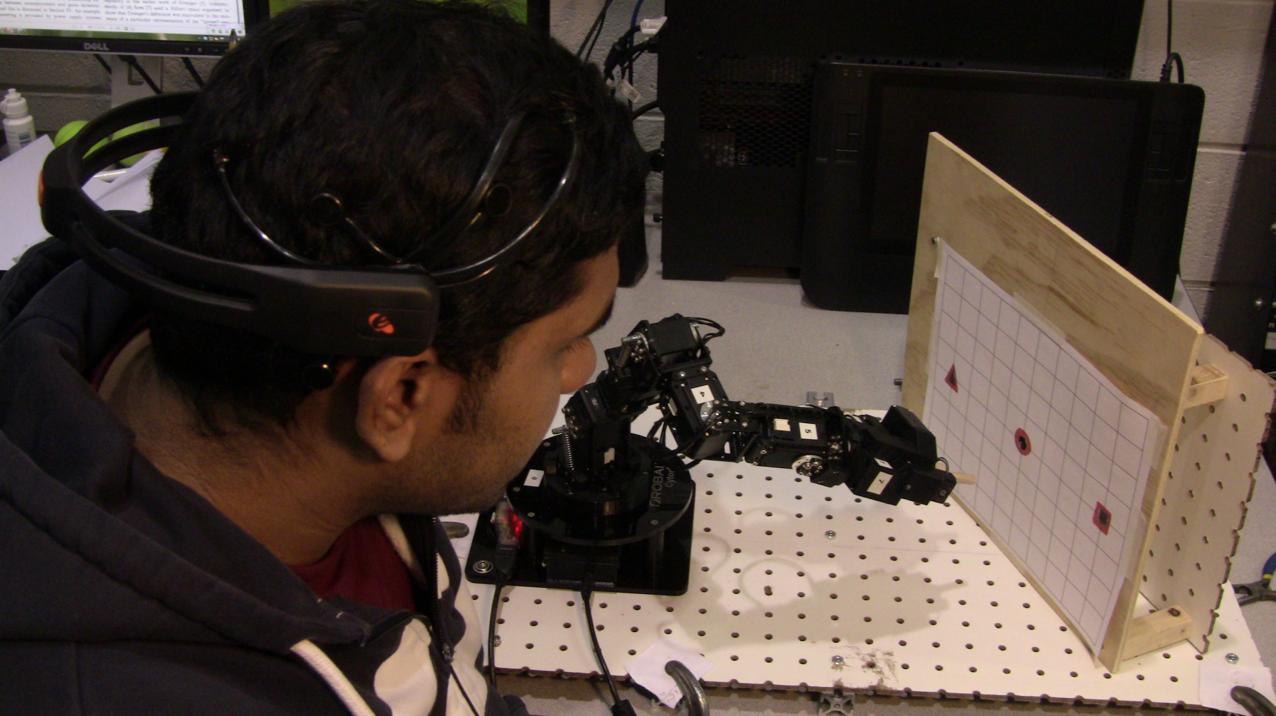 UB student Habib Mohd Younu wearing a headset that directs a mind controlled robot to place a peg in a hole.