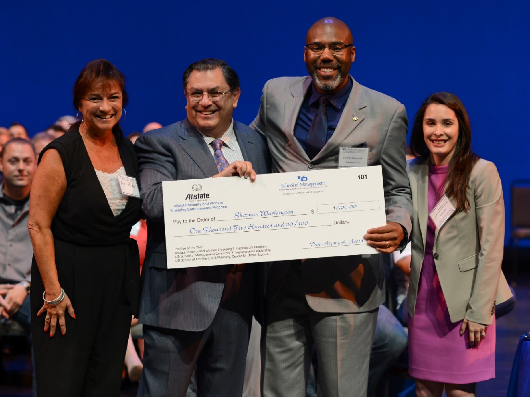 From left, Mentor of the Year Lori E. Miller; Arjang Assad, dean of the UB School of Management; Sherman Washington, owner of 1 Accord Services Inc., and Alex Cleary, MWEE program coordinator, celebrate Washington&rsquo;s Prot&eacute;g&eacute; of the Year award, holding an over-sized check. 