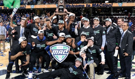 The UB men's basketball team posing on the basketball court. 