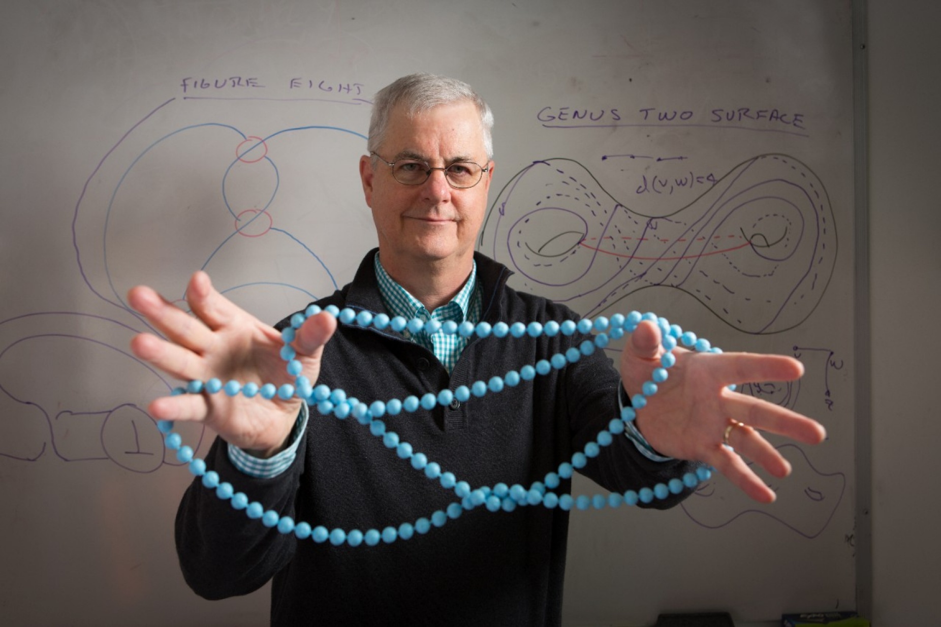 UB knot theorist Bill Menasco holding a string of beads.