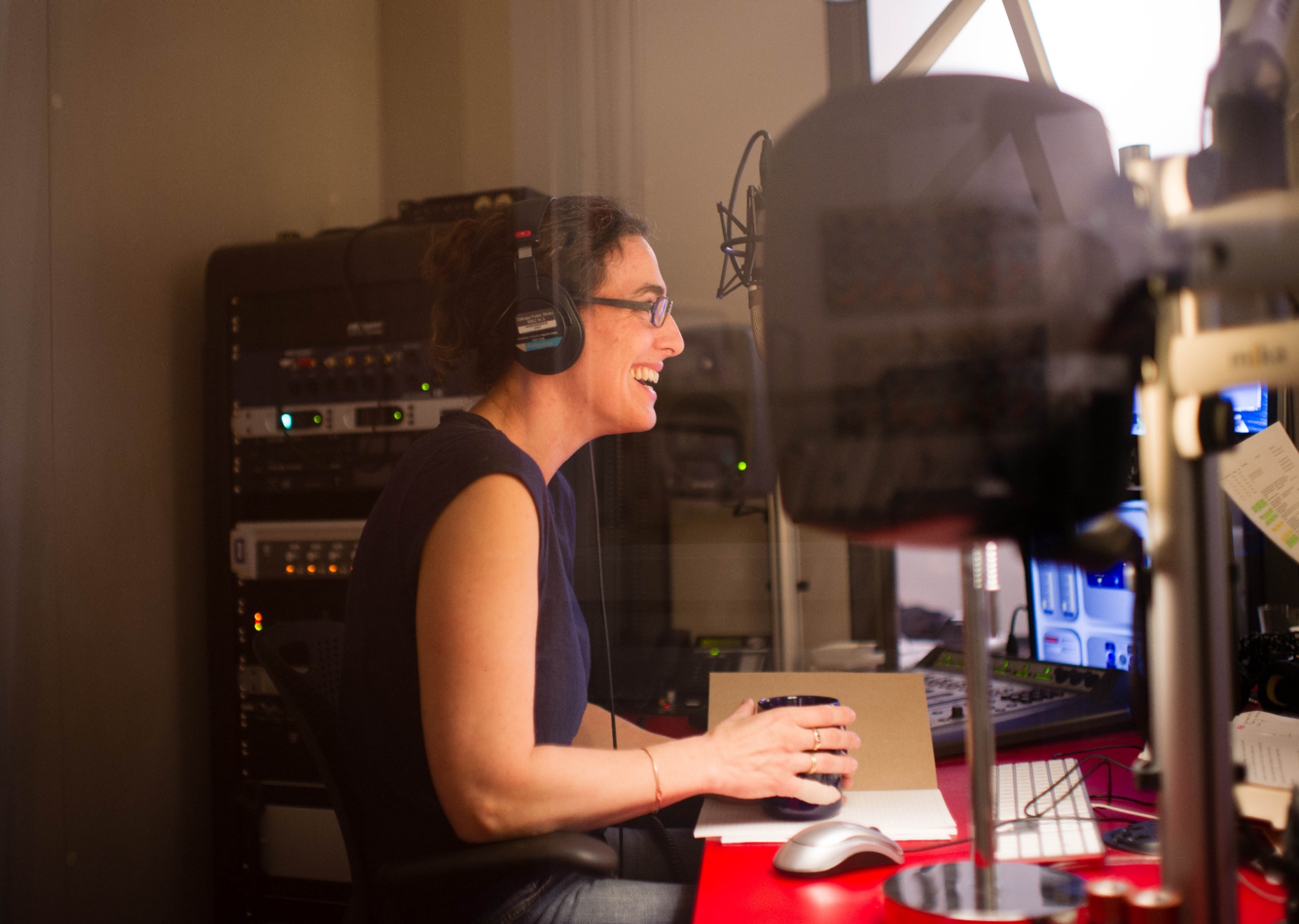 Sarah Koenig wearing headphones in front of a microphone. 