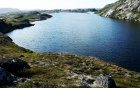A blue lake surrounded by a green and rocky landscape. 