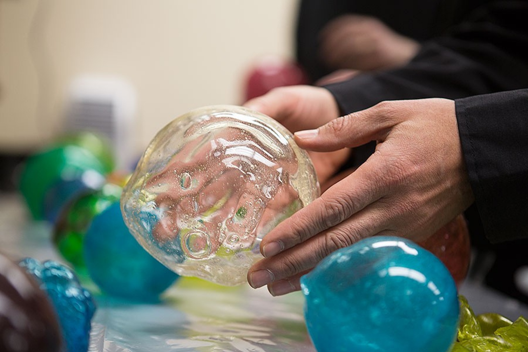 Close up of hands holding a transparent gelatinous sphere.