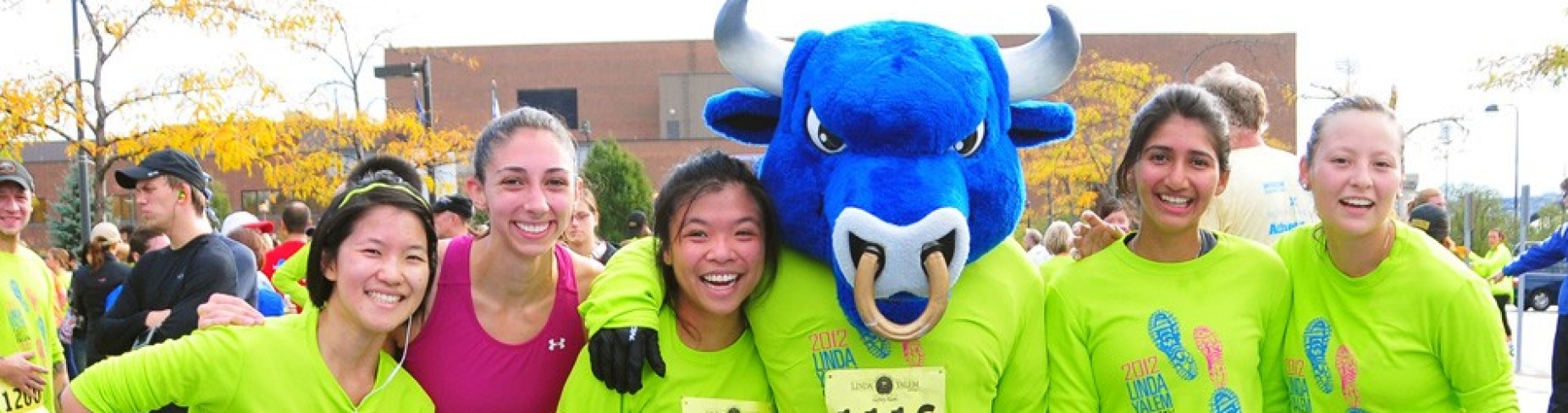 People smiling while posing with UB mascot Victor E. Bull during Linda Yalem Run. 