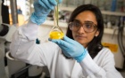 A scientist in a lab coat with a flask of glowing dye. 
