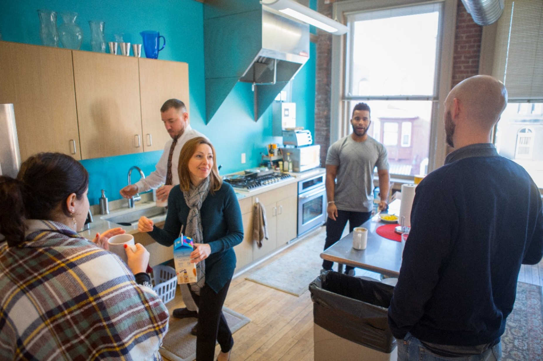 Five coworkers standing in a brightly lit kitchen. 