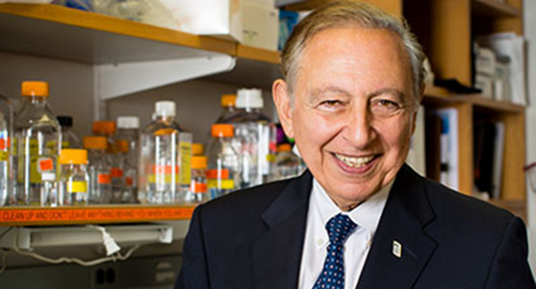 Robert Gallo sitting in a lab while wearing a suit.