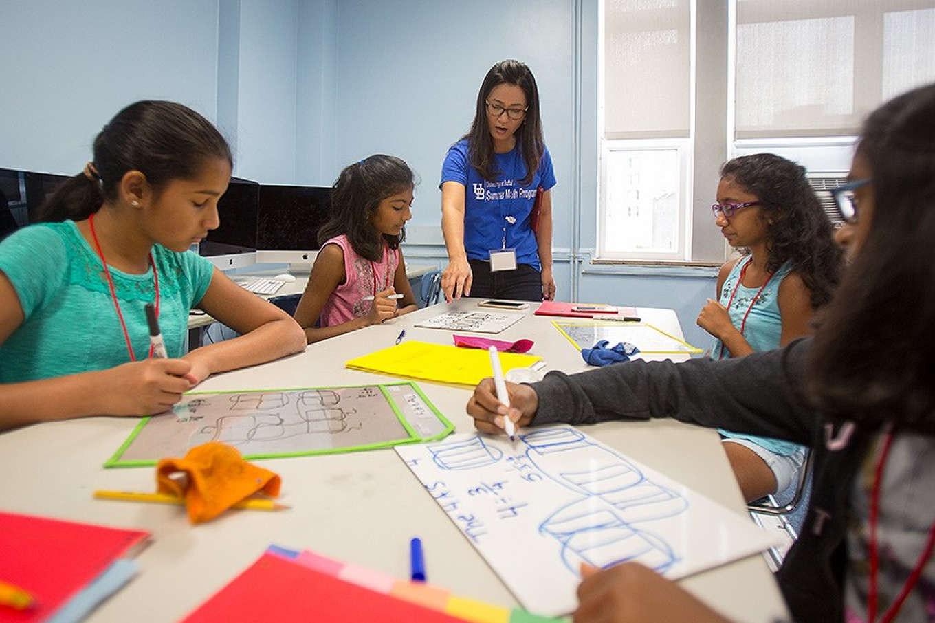 An instructor leads several adolescent female students through an activity during the Summer Math Program. 