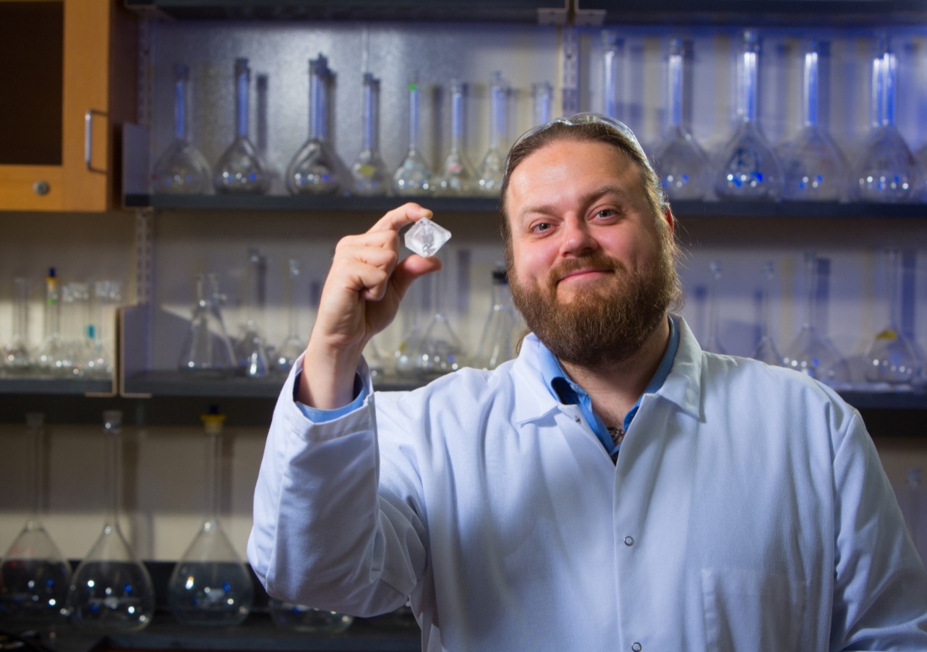 A scientist holding a crystal in the lab. 