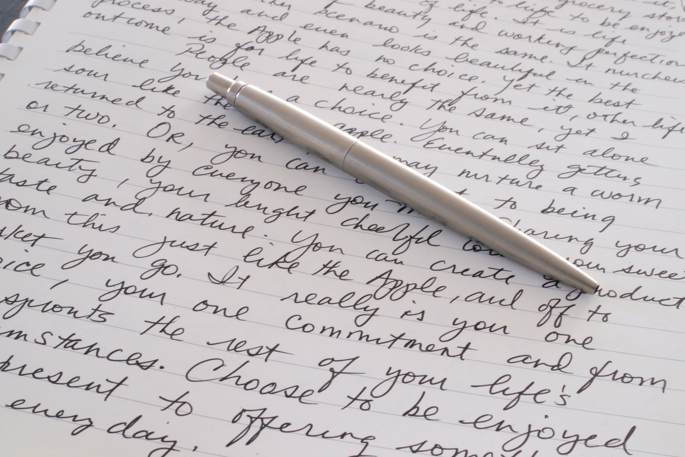 A silver pen sits on a page with words written on it. 