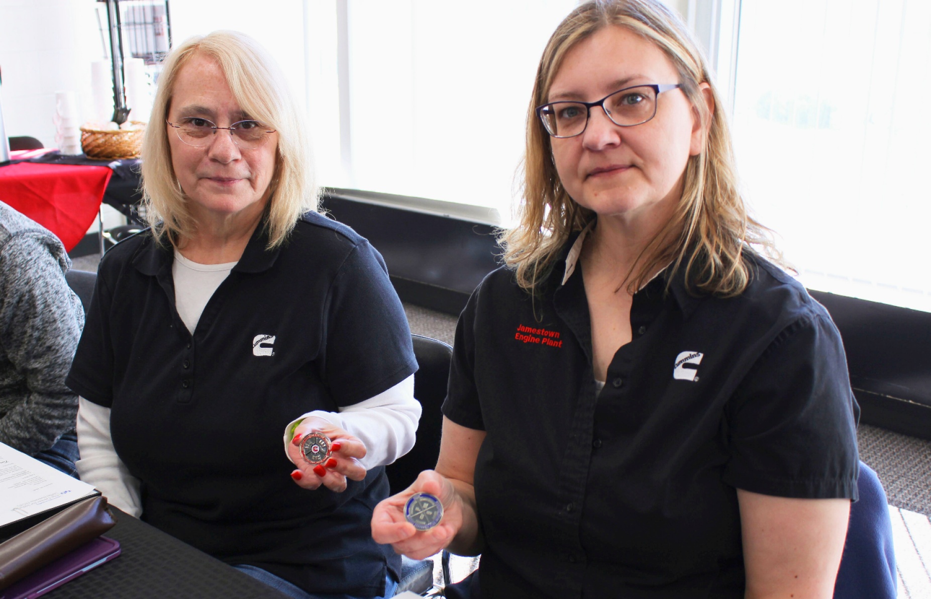 From left, Myra Olson and Tammy Emerson show off the coins given to them by Cummins Jamestown Engine Plant upon receiving their Certified Production Technician certificates. 