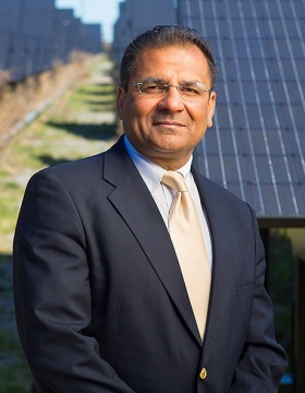 Amit Goyal stands in front of solar power field. 