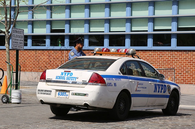 A school safety officer and his vehicle parked in front of a school building.