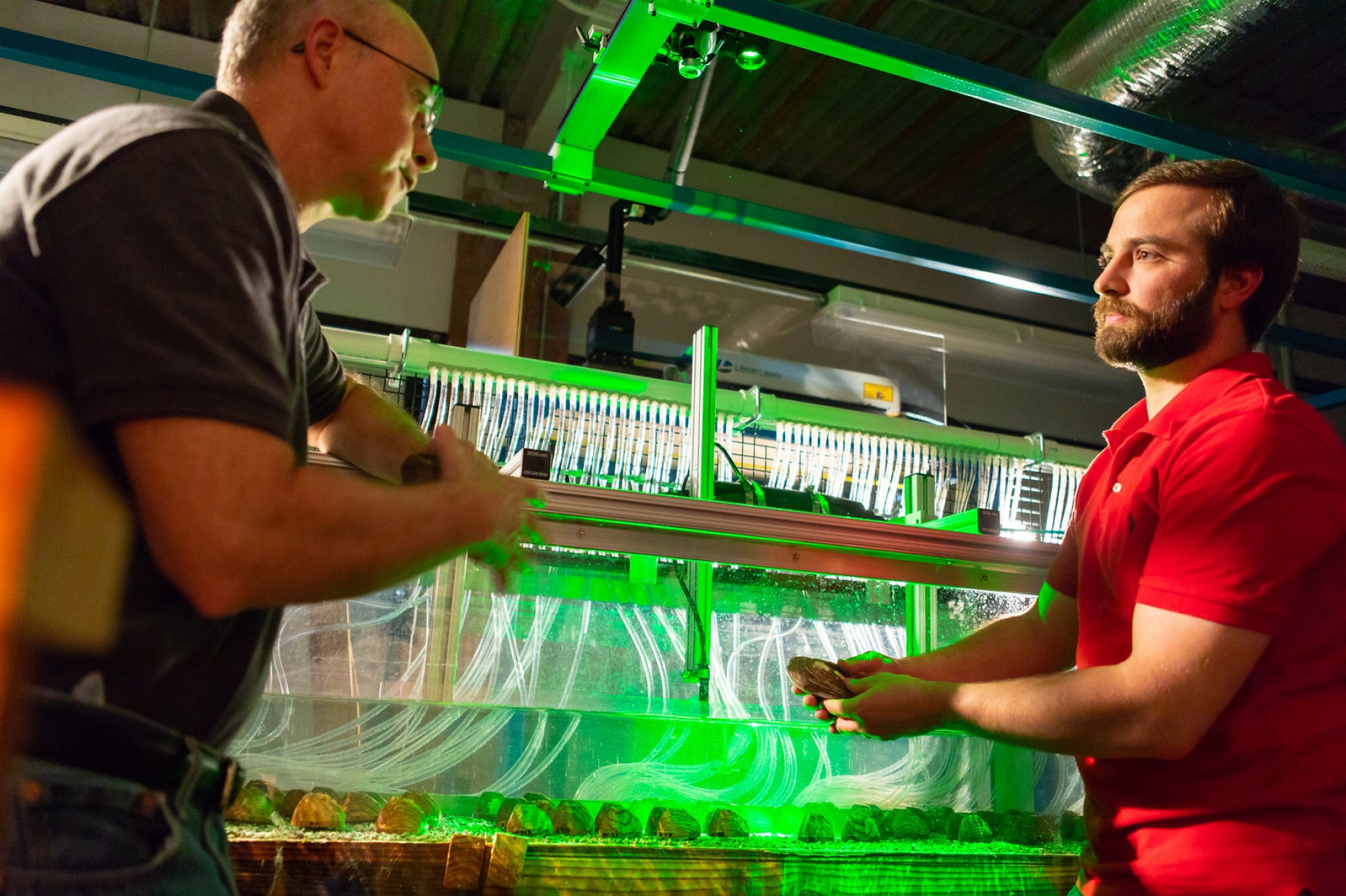Brandon Sansom, PhD student, stands in front of mussel flume with advisor Sean Bennett, chair of geography.