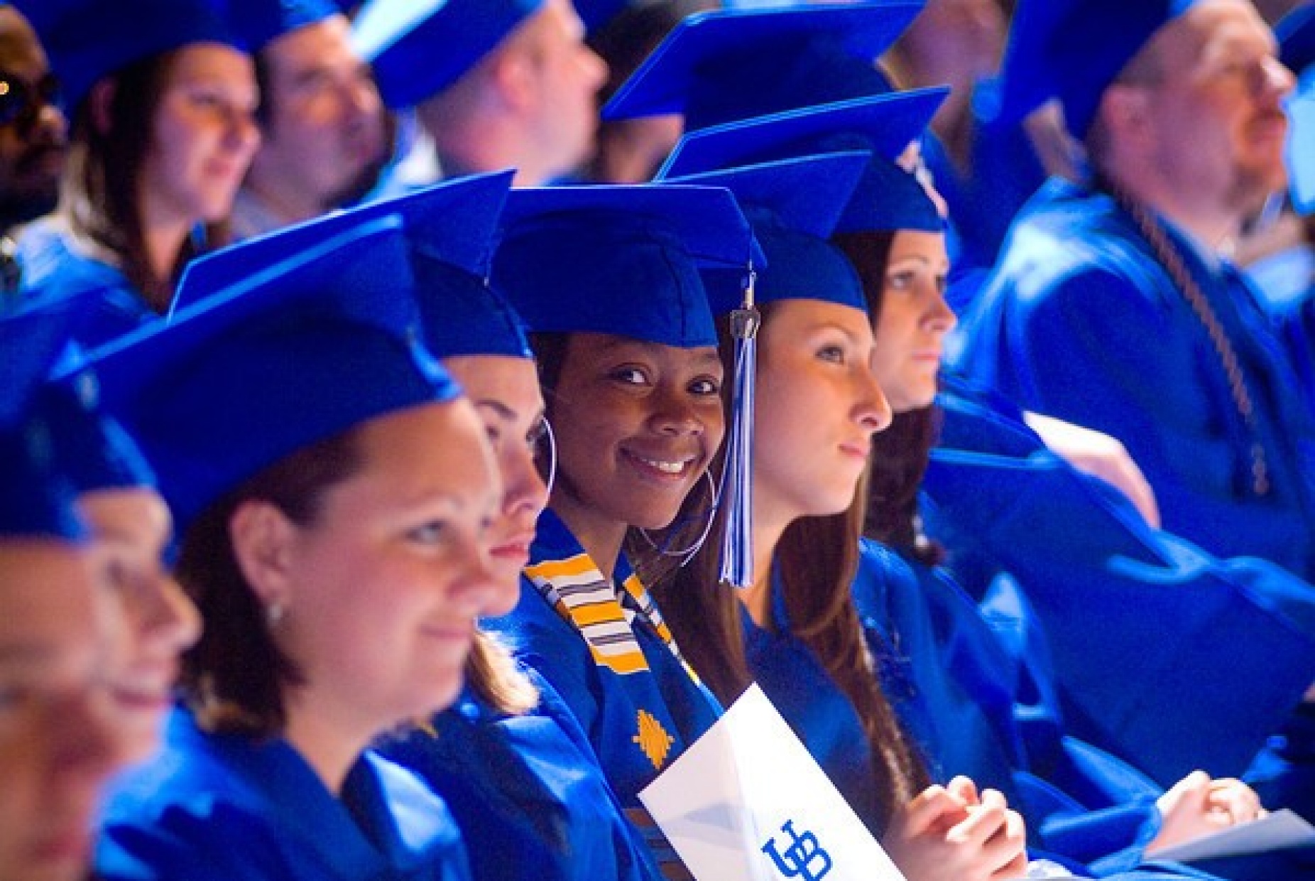 Students seated wearing caps and gowns. 