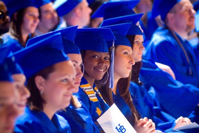 Students seated wearing caps and gowns. 
