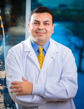 Dhaval Shah in lab coat next to equipment. 