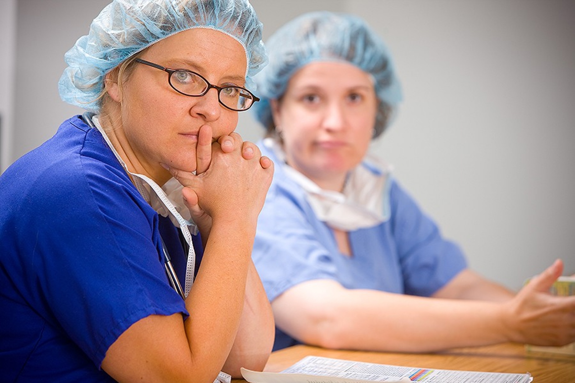 Women in scrubs sitting at table. 