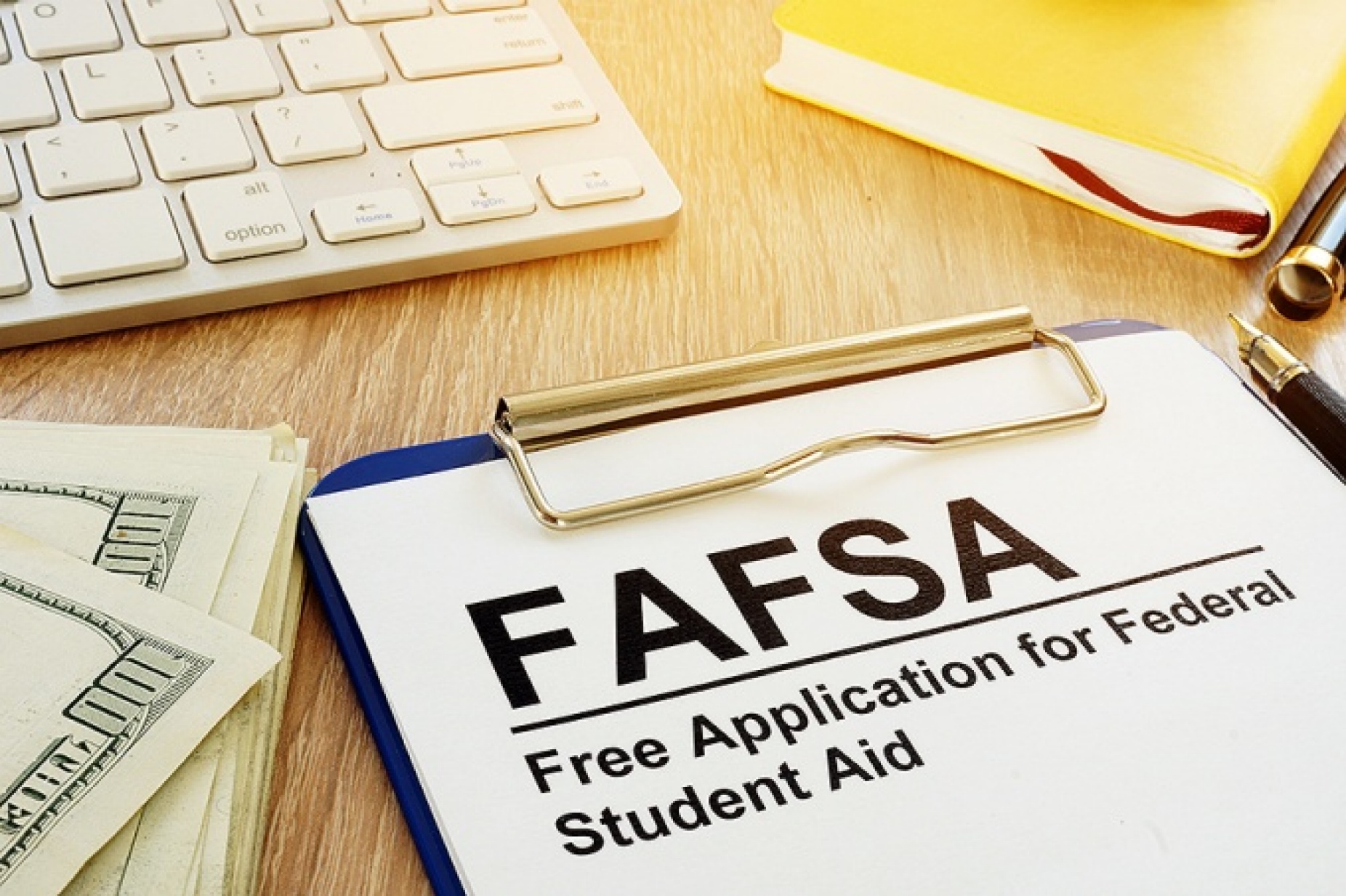 Financial aid concept featuring money, a keyboard and a FAFSA form on a clipboard. 