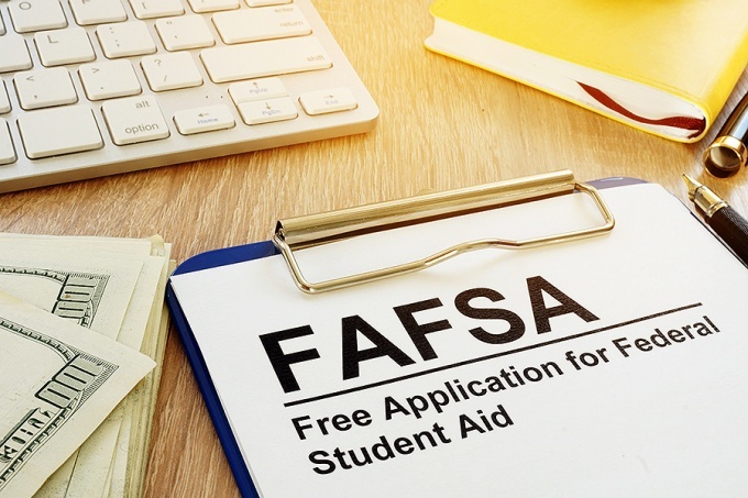 Financial aid concept featuring money, a keyboard and a FAFSA form on a clipboard. 
