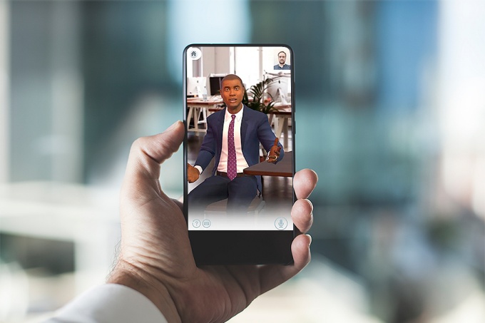 A man's hand holding a smartphone with an avatar displayed on the screen. 