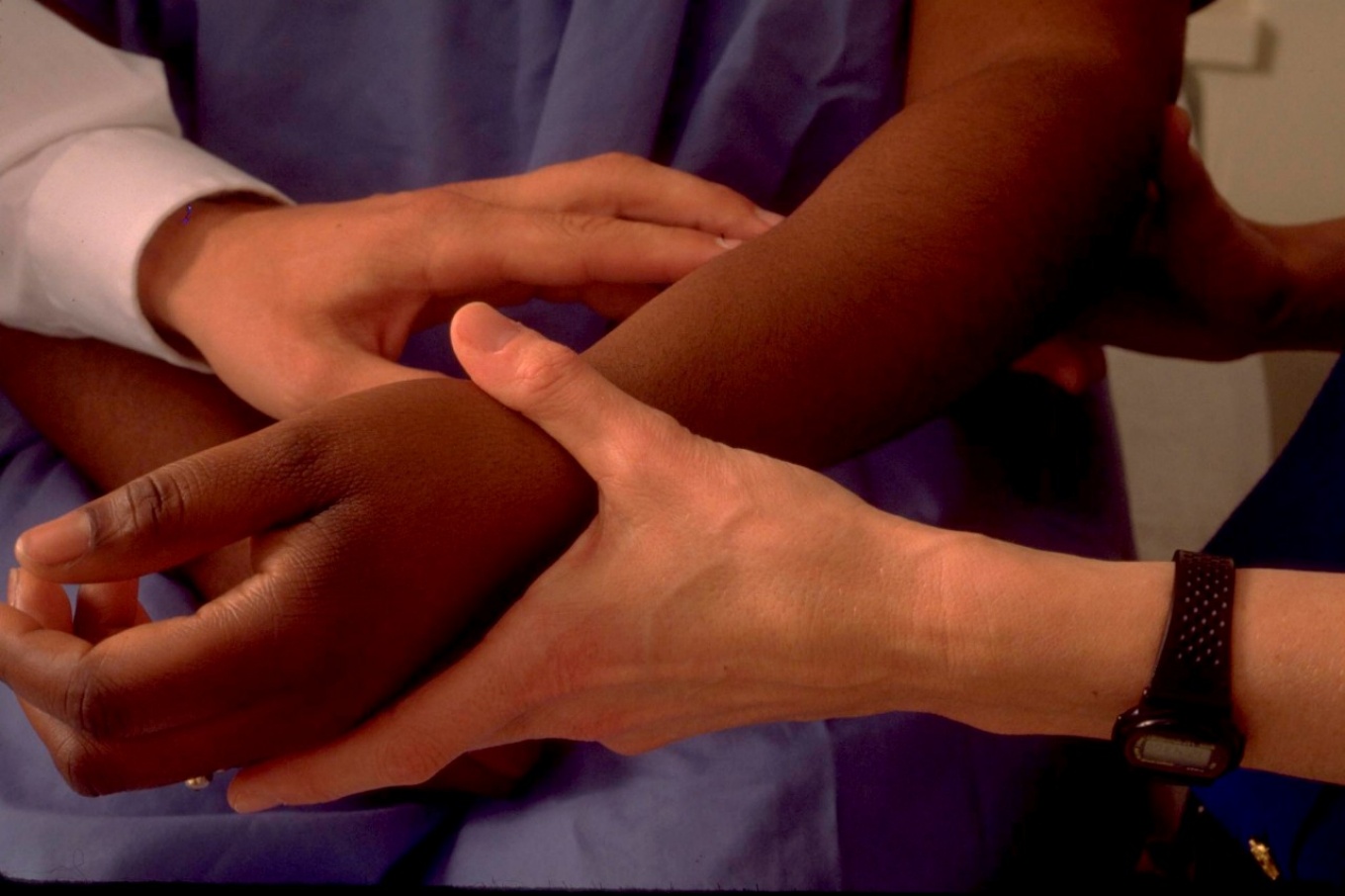 Hands of doctor examining wrists of patient. 