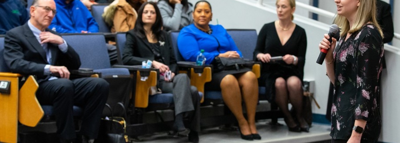 Photo of UB researcher Jessica Kruger speaking into a microphone while standing at the front of the classroom.