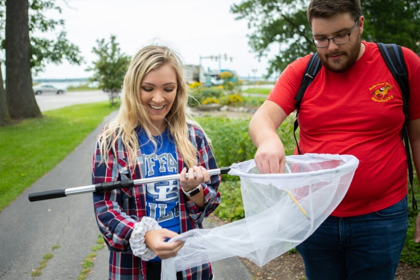 Zoom image: Cassandra Rivier (left), a UB junior in environmental geosciences, and Robert Graham, a UB senior in biological sciences, hold a butterfly in a net during an ecological methods course taught through the Department of Environment and Sustainability. As part of the class, students captured, tagged and released monarch butterflies monarch butterflies to help track the insects&rsquo; spectacular migration. Credit: Douglas Levere / University at Buffalo 