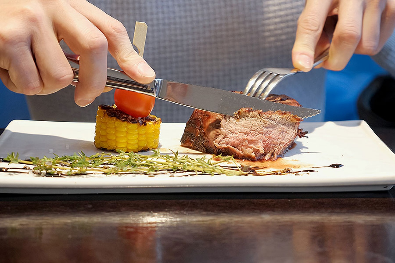 Close-up view of a man cutting off a piece of steak.