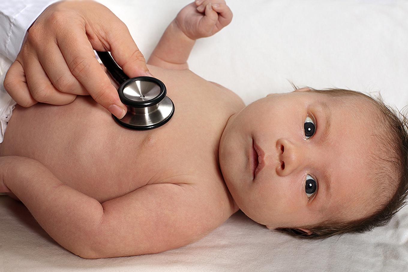 A pediatrician listens to a baby's heart. 