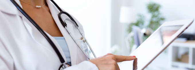 Photo of a female physician reviewing information on a tablet. 