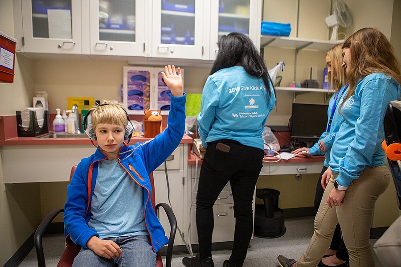 Young boy raises hand during hearing test. 