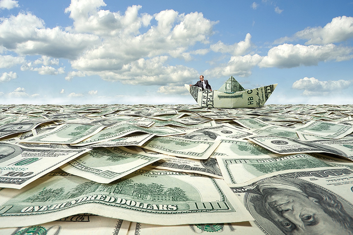 Concept of self-worth based on financial success: a lone man in a paper money boat on an ocean of dollar bills.