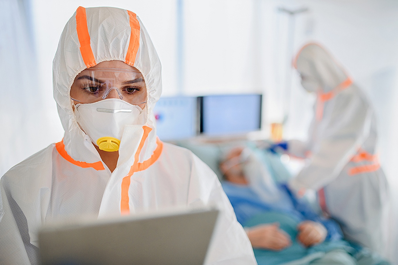 Doctors with protective suits in hospital with patient. 