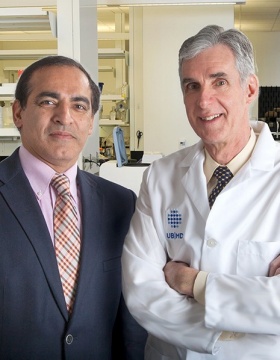 Sanjay Sethi (left) with Tim Murphy in white coat standing in lab. 