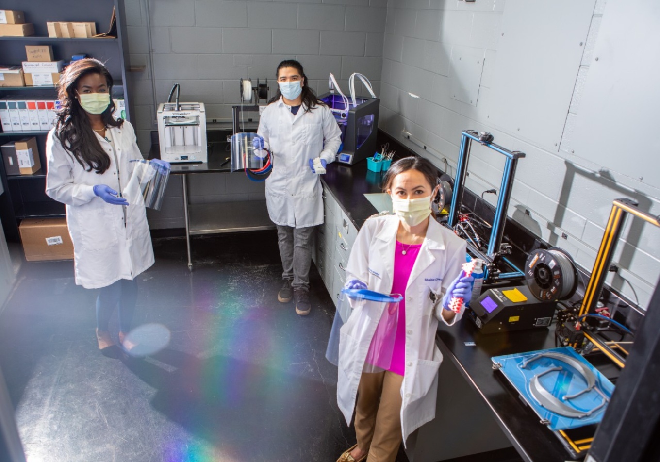 Students holding PPE in lab. 