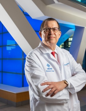 Steven Lipshultz in white coat, standing in lobby of Jacobs School of Medicine and Biomedical Sciences. 