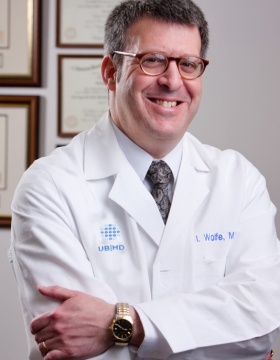 Gil Wolfe in white coat, arms folded. 
