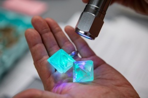 Zoom image: Williamsville South High School science teacher Jeff Yap demonstrates glowing crystals his class created using highlighter ink for a past edition of the U.S. Crystal Growing Competition. Credit: Douglas Levere / University at Buffalo 