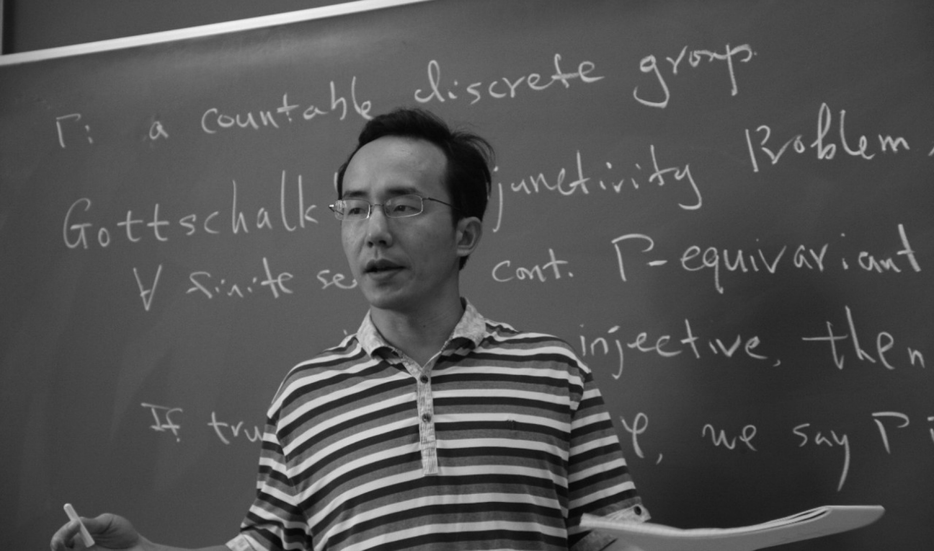 Hanfeng Li standing in front of a chalk board. 